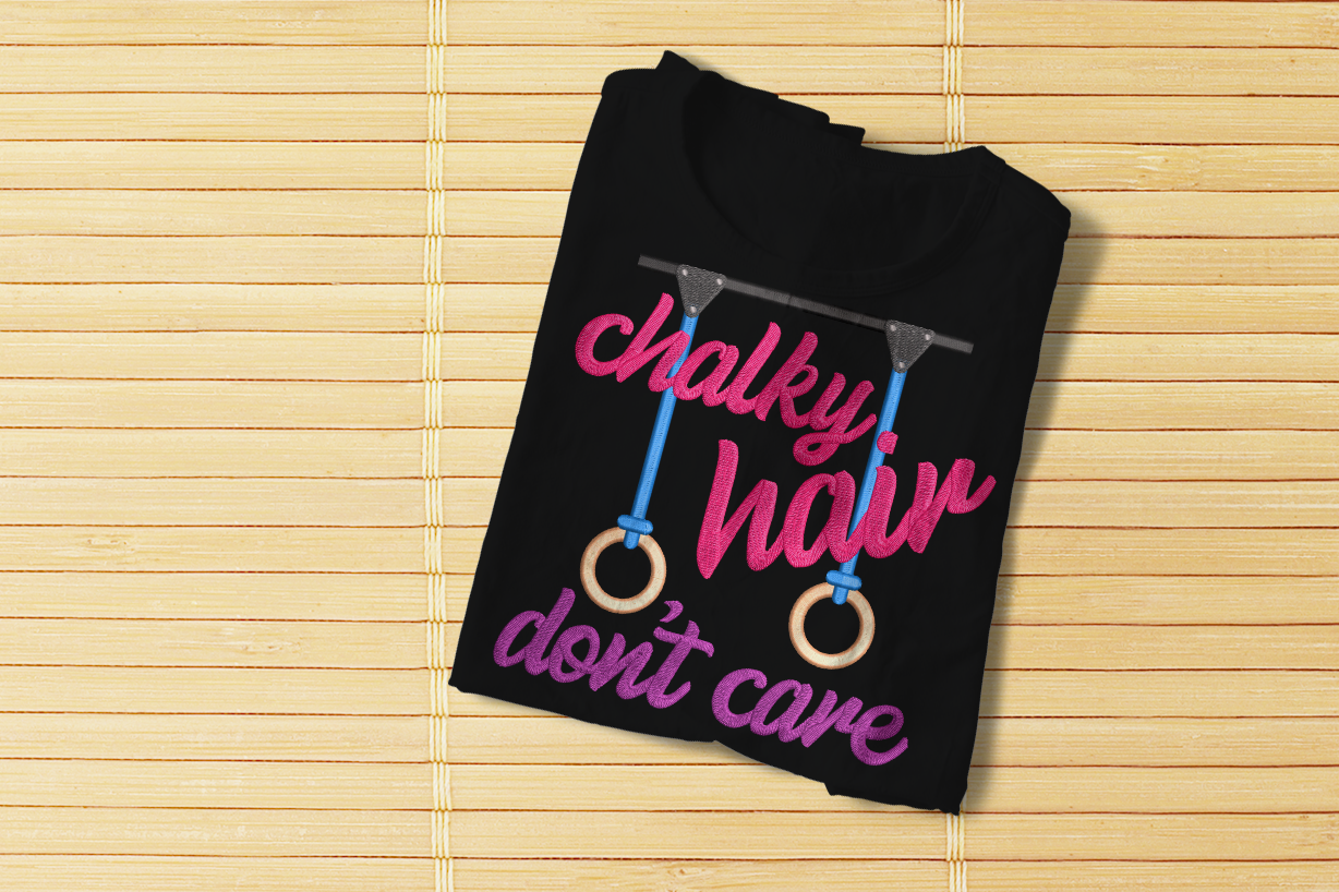 Folded tee with embroidered gymnastic rings and words "chalky hair don't care"
