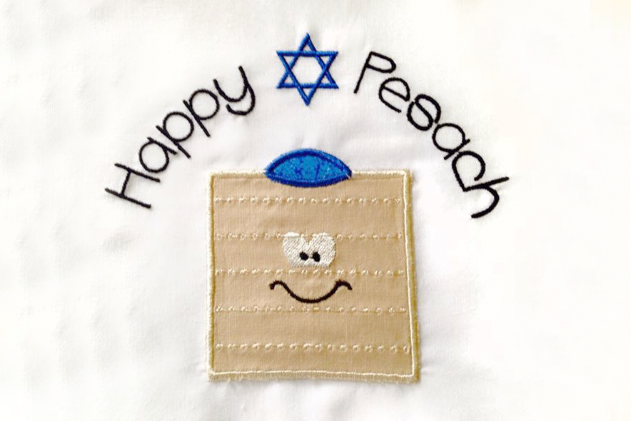 Applique of a cartoon matzo with a yarmulke. Above it says "Happy Pesach" with a star of David between the words.