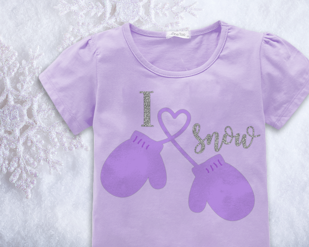 Child's shirt says "I heart snow." There is a pair of mittens and the string connecting the mittens makes the heart.