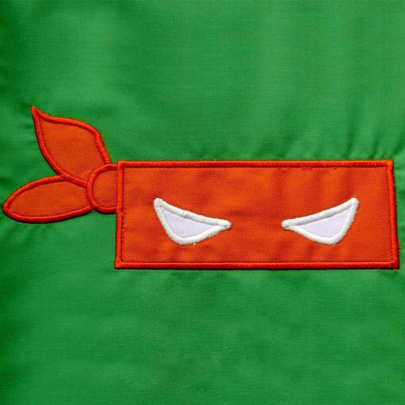 Orange blindfold mask applique on a green background.