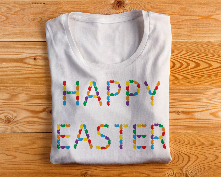 Folded shirt with a design that says "Happy Easter" spelled out of jelly beans