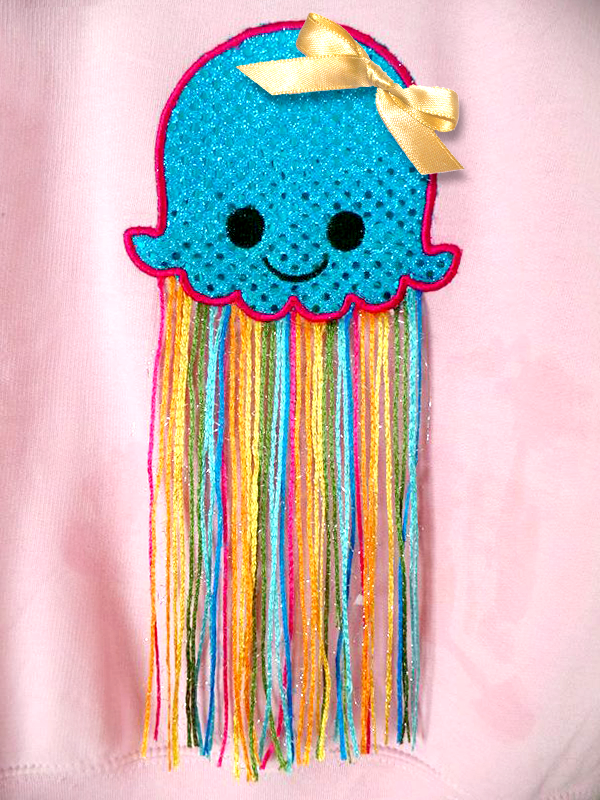 Cute smiling applique jellyfish. A real ribbon has been added and the tentacles are made from multicolored yarn.