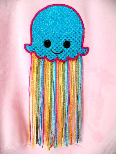 Cute smiling applique jellyfish. The tentacles are made from multicolored yarn.