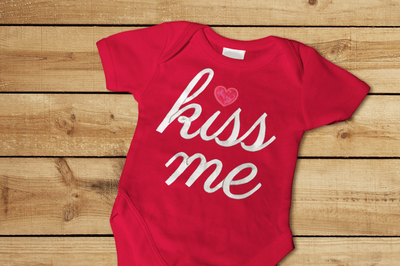 Applique design that says "kiss me" with a heart for the dot over the i.