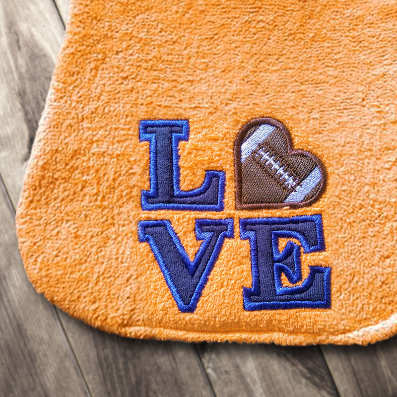 Applique of the word "LOVE" set square. In place of the O is a heart with football details on it.