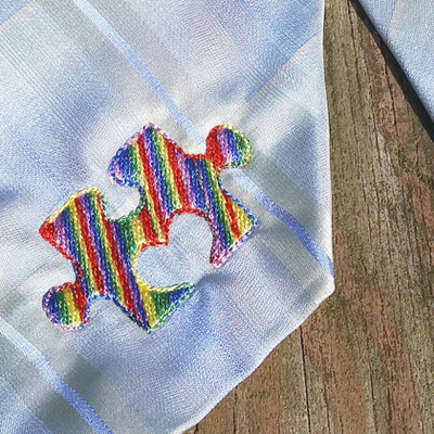 Embroidery of a puzzle piece with a heart shaped notch.