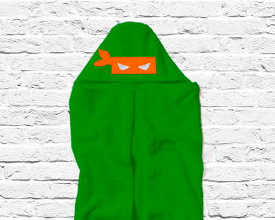 Orange blindfold mask applique on a green hooded towel.