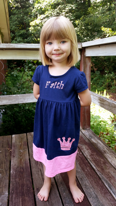 Little white girl wearing a dress with a princess crown applique