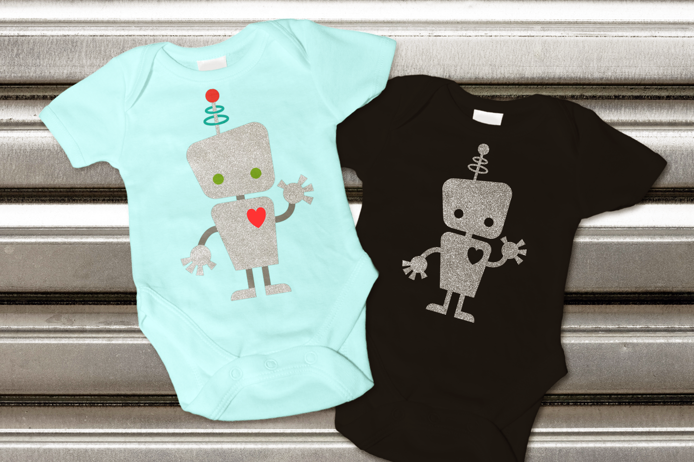 Two baby onesies with the design of a cute waving robot.