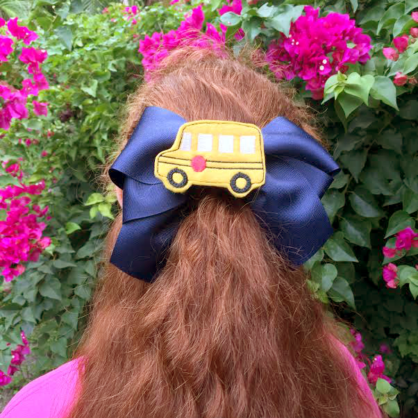 School bus feltie on a bow being worn by a girl with red hair