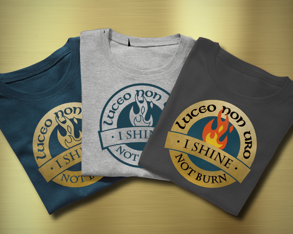Three folded tees. Each has a circular design that says "Luceo non uro I shine not burn" with a flame