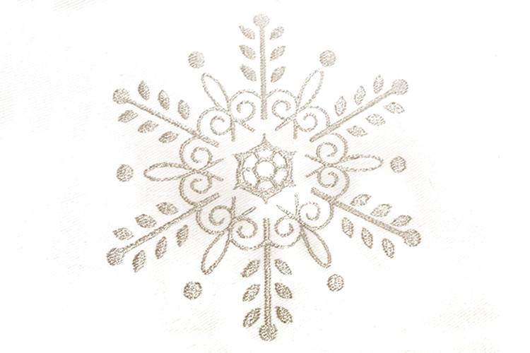 An intricate silver snowflake embroidery on white fabric.