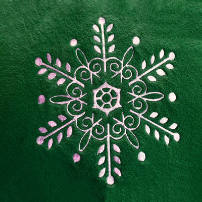 An intricate white snowflake embroidery on green fleece fabric.