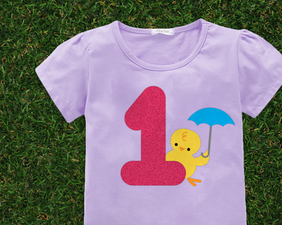 Lavender shirt with a large pink 1 with a chick holding an umbrella behind the number.