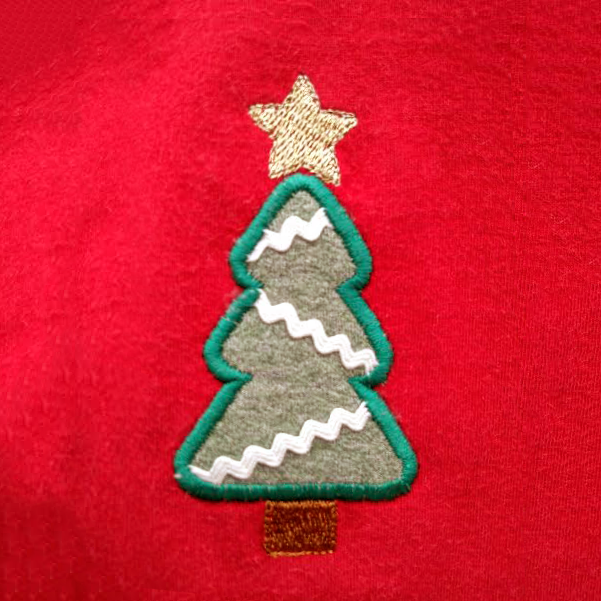 Close up of an applique Christmas tree on red fabric.