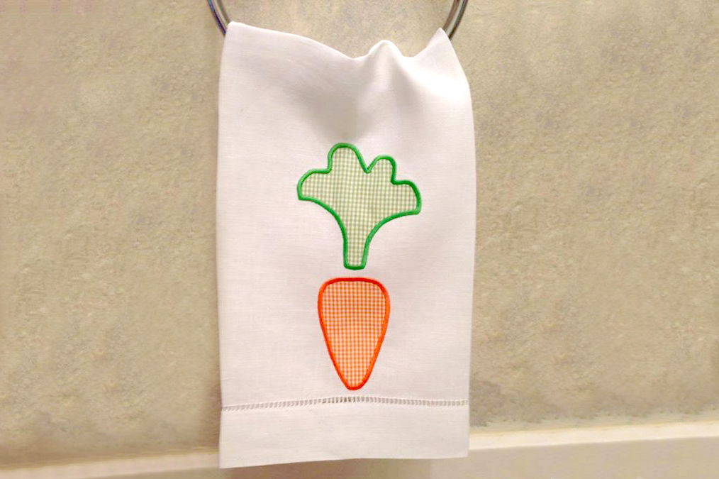 A white tea towel with a cute carrot applique.
